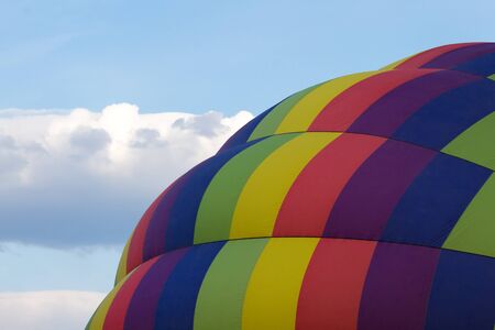 A multi color hot air balloon with a close up view against a cloudy blue skyの写真素材