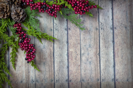 Christmas Garland with Pine Cones and Berries on a wood plank board with room for writing or text in...