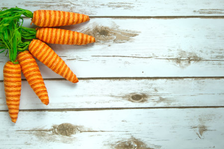 Orange striped faked carrots on a rustic whitewashed wood background with room for text