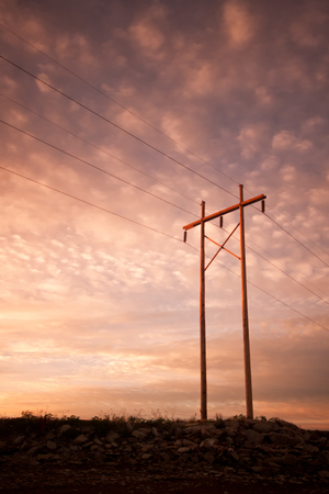 Power or Electrical lines at sunrise or sunset with clouds lighting up the skyの写真素材