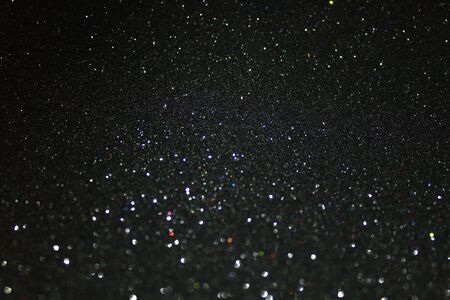 Glittering black background. Twinkling particles of glitter.の写真素材
