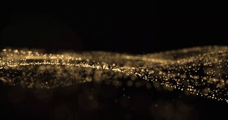 Golden glitter and sparkling light particles wave, glittering dust flow splash. Gold bokeh light glow, shimmering sparks flow overlay on black backgroundの写真素材