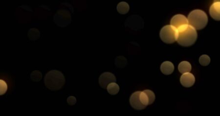 Bokeh light background, gold shine abstract blur flare effect. Golden yellow glitter particle flares with bright glowing shiny bokeh light sparkles on black backgroundの写真素材