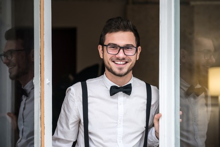 Groom in white shirt smiling near the windowの写真素材