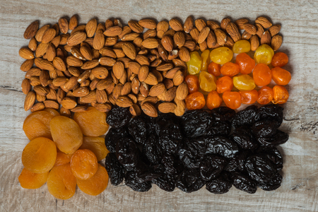 prunes, dried apricots, dried mandarins and almonds on a light wooden background.の写真素材