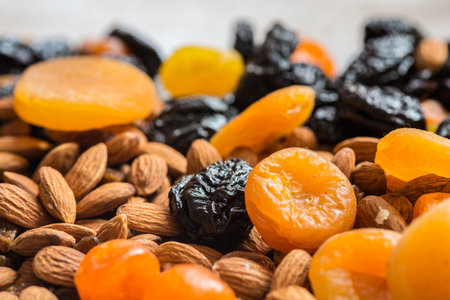prunes, dried apricots, dried mandarins and almonds on a light wooden background.の写真素材