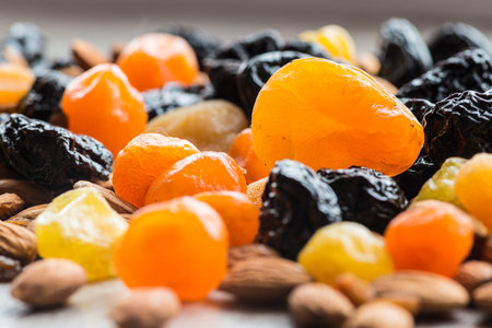 prunes, dried apricots, dried mandarins and almonds on a light wooden background.