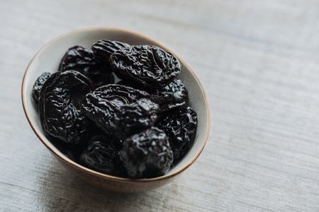 prunes in brown plate on a white background. Close-up.の写真素材