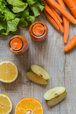 Fresh carrot juice in bottles on a grey wooden table.の写真素材