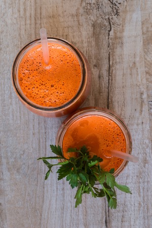 Fresh carrot juice in bottles on a grey wooden table.の写真素材