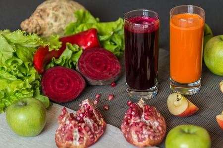 two glasses of different fresh juice. Beet and carrot juices on grey wood backgroundの写真素材