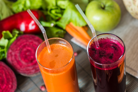 two glasses of different fresh juice. Beet and carrot juices on grey wood backgroundの写真素材