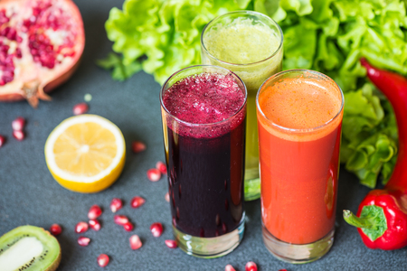 three glasses of different fresh juice. Beet, carrot and kiwi juices on grey backgroundの写真素材