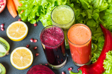 three glasses of different fresh juice. Beet, carrot and kiwi juices on grey backgroundの写真素材