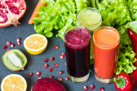 three glasses of different fresh juice. Beet, carrot and kiwi juices on grey backgroundの写真素材