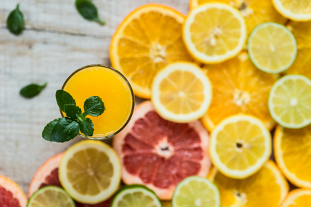 glass of orange juice on the wood background with slices of citrusの写真素材