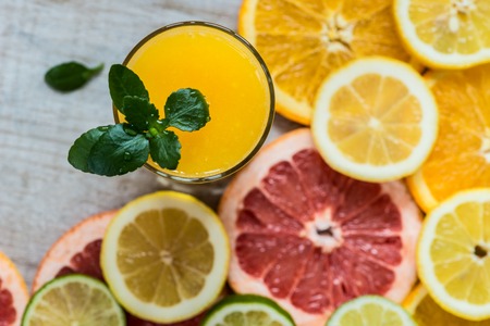 glass of orange juice on the wood background with slices of citrusの写真素材