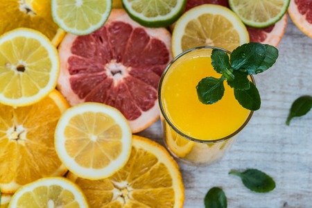 glass of orange juice on the wood background with slices of citrusの写真素材
