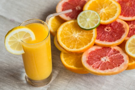 glass of orange juice on a linen background with slices of citrusの写真素材