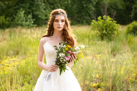 young redheaded girl walk in the park with bouquet of flowersの写真素材