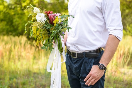handsome man hold wedding bouquet in his handの写真素材