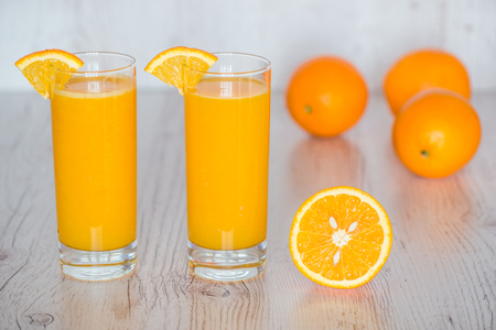 orange juice in glasses at light wooden backgroundの写真素材