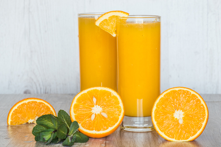 orange juice with mint in glasses at light wooden backgroundの写真素材