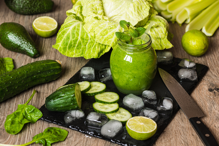 Detox diet. Green smoothie with different vegetables on wooden backgroundの写真素材