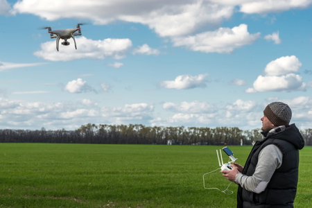 man operating of flying drone quadrocopter at the green field