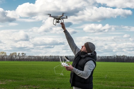 man holding of flying drone quadrocopter at the green fieldの写真素材