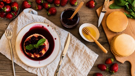 top view stack of homemade american pancakes served with jam and strawberries on wooden backgroundの写真素材