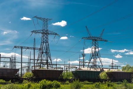 Freight train is passing by thermal power stations and power lines. Distribution electric substationの写真素材