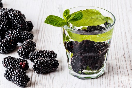 detox water with blackberry and mint in glass on white wooden background.の写真素材