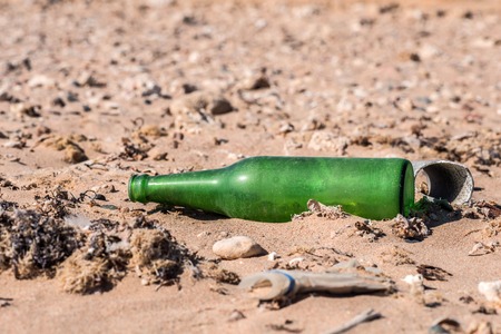 old green empty glass bottle on the sand. Macro.の写真素材