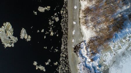 Aerial view landscape with trees, frozen water, ice and snow on the Dnieper river in Kiev. Ice comes to the river bankの写真素材