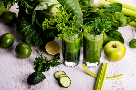 Green smoothie with fruits and vegetables on white wooden background.の写真素材