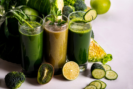 Different healthy vegan spinach, kiwi and cucumber drinks on the white wooden background. Raw drinks and foods.の写真素材