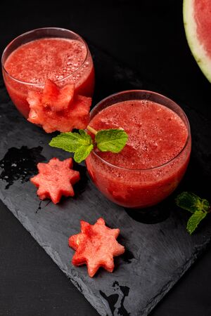 Watermelon smoothie fresh juice with mint and pieces in the shape of stars on a black background. Summer healthy drinks. Close-up.の写真素材