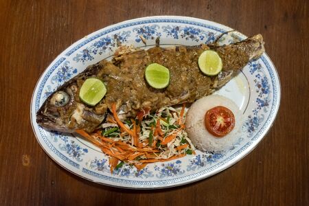 Grilled ocean fish with a side dish and salad on a wooden table.の写真素材