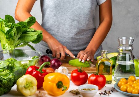 Woman cuts avocado and cooking salad in the kitchen. Healthy diet conceptの写真素材