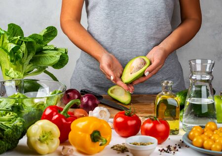 Avocado in female hands. Woman about to cook salad in a glass bowl in the kitchen. Healthy diet conceptの写真素材
