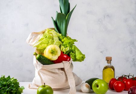 Eco-friendly fabric bag full of fresh vegetables on the kitchen table. Zero waste purchases concept.の写真素材