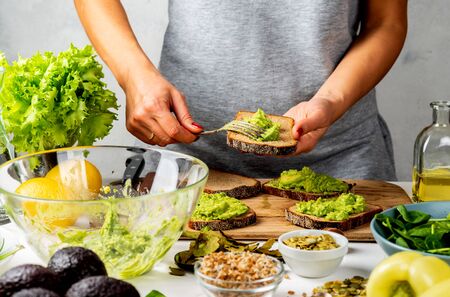 Woman cooking avocado sandwiches in a kitchen. healthy food conceptの写真素材