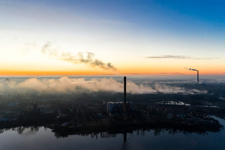 Power plant smokestacks at sunrise near the lake. Environmental pollution