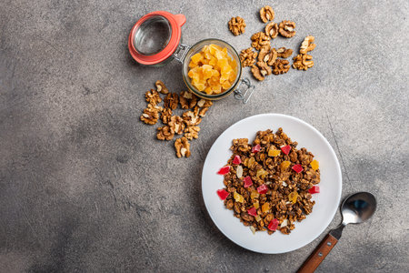 Granola with dried fruits in a white plate on a gray background.