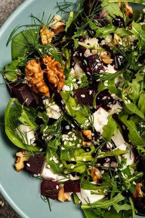 Salad with beets, ruccola, parsley, herbs, feta cheese, walnuts in a bowl. Close upの写真素材