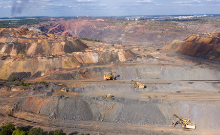 open pit quarry with a lot of equipment at work aerial view.