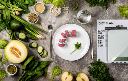 Eating control Diet concept. Measuring tape on the plate Diet plan Kitchen scales and healthy food set.の写真素材