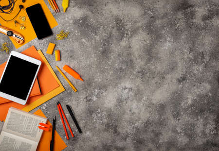 Workspace with orange office accessories and gadgets. Top view with copy spaceの写真素材