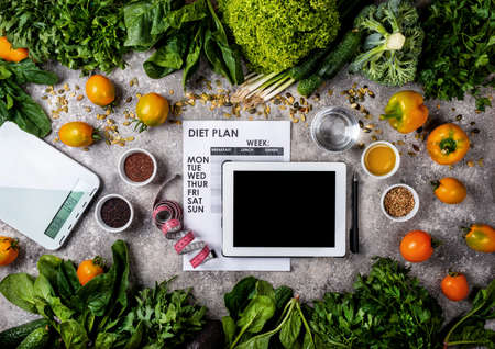 Healthy eating and weight loss concept. Tablet computer Diet plan and set of clean food.の写真素材